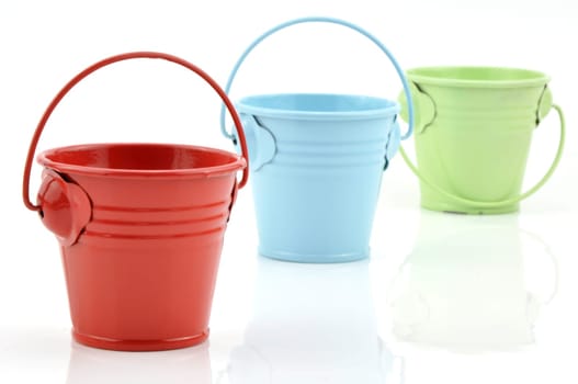 Three metal buckets of different colours with handle, isolated on white background