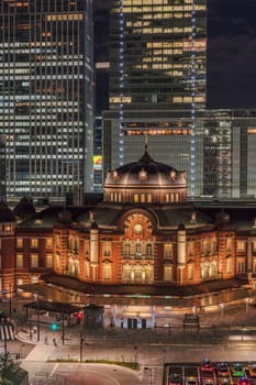 Marunouchi side of Tokyo railway station in the Chiyoda City, Tokyo, Japan.  The station is divided into Marunouchi and Yaesu sides in its directional signage. The station first called Central Station was built in 1914 directly in front of the Imperial Palace gardens. The three-story station building was designed by architect Tatsuno Kingo who also designed Manseibashi Station and the nearby Bank of Japan building. Much of the station was destroyed in B-29 firebombing on May 25, 1945. The bombing shattered the impressive rooftop domes. The station was quickly rebuilt within the year, but simple angular roofs were built in place of the domes, and the restored building was only two stories tall instead of three.