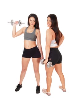 Two pretty women in exercise outfits standing in the studio working.out with there dumbbells, isolated for white background.