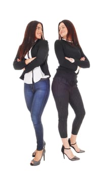 Two beautiful young woman standing back to back in jeans and heels.looking at each other, isolated for white background.