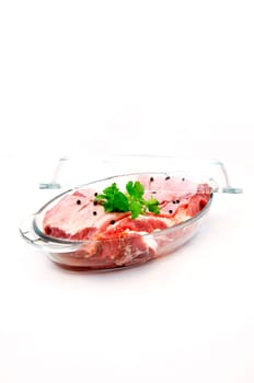 Fresh red meat with seasoning in glass pan ready to cook