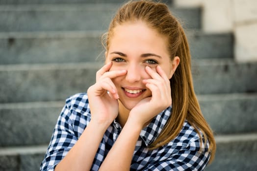 Teenager portrait - smiling girl outdoor with hands before face