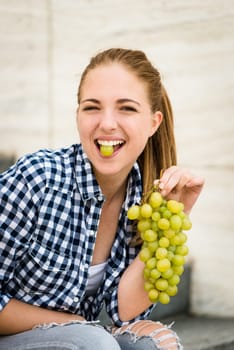 Young woman eating grapes outdoor - holding grape between teeth