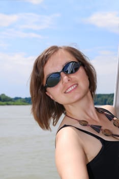 Young smiling woman rests over rail on boat river trip
