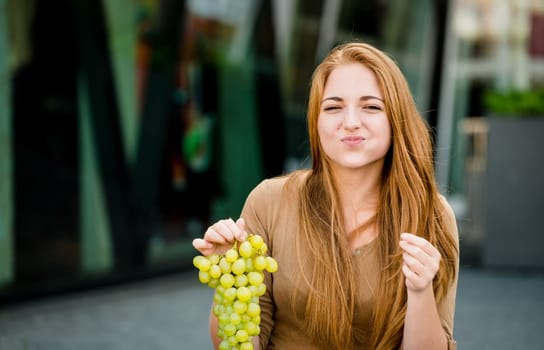 Young woman - teenage girl eating grapes outdoor in street
