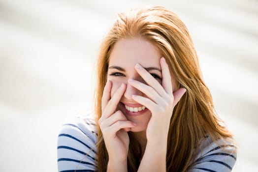Teenager portrait - smiling girl outdoor with hands before face