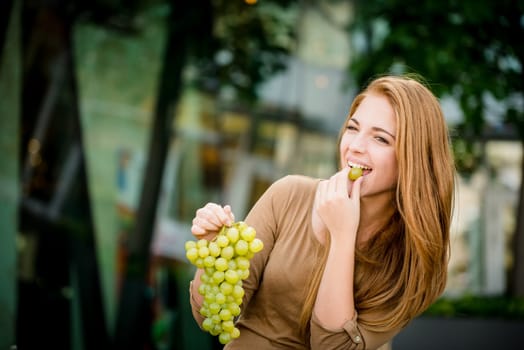 Young woman - teenage girl eating grapes outdoor in street