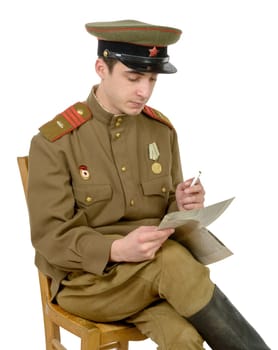 a young Soviet officer sitting in a chair read a newpaper