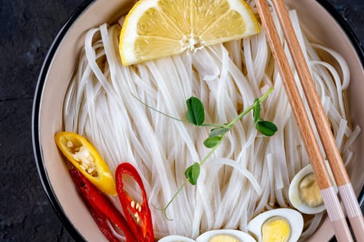 Rice noodles, Asian cuisine, with quail eggs, chili pepper and pea sprout, close-up