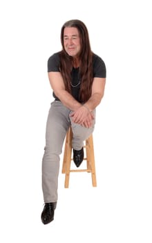 A happy indigenous man sitting for a portrait image on a chair with.his long brunette hair, isolated for white background.