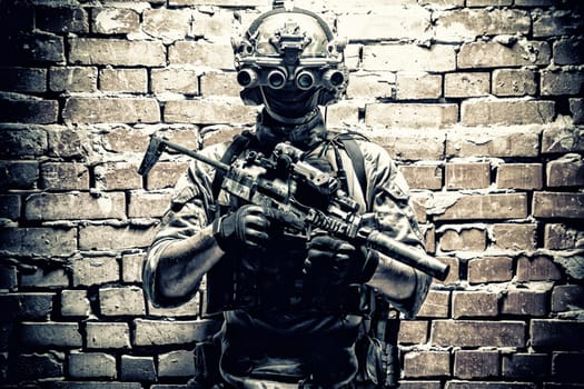 Army special forces tactical group fighter in cqb mission, using radio headset, looking through four lens night-vision, thermal imaging device on helmet, armed small submachine gun with silencer