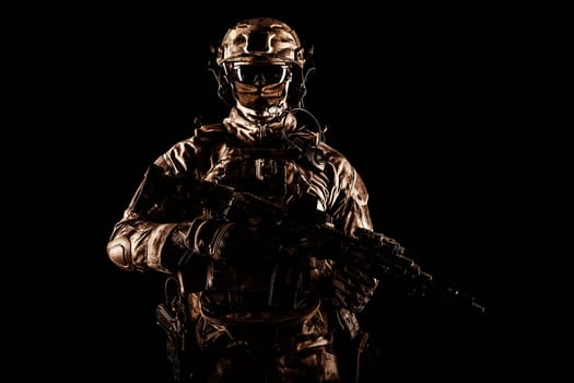 Army special operations forces soldier in mask and combat uniform, armed submachine gun, low key studio portrait on black, copyspace contour shot