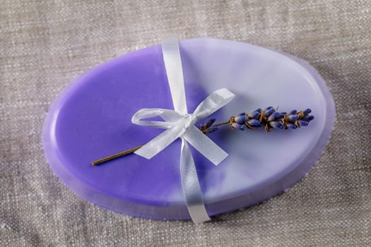 Handmade glycerin soap in delicate violet colors with a white bow and lavender on a linen napkin