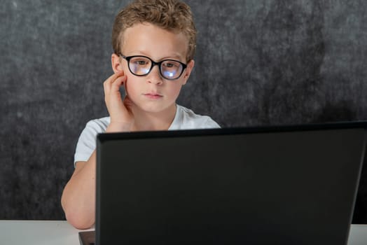 a serious boy sitting with laptop computer