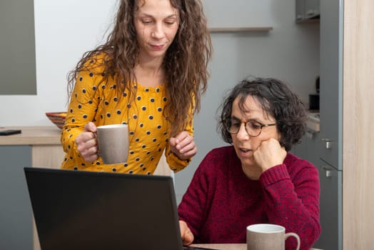 Young woman helps senior on a laptop computer