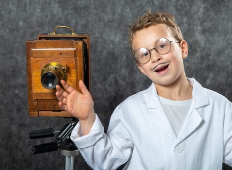 cheerful boy retro photographer with a vintage wooden camera
