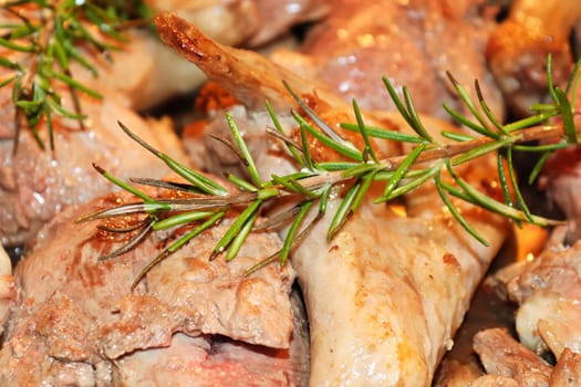 Closeup of rosemary over cut up duck pieces.