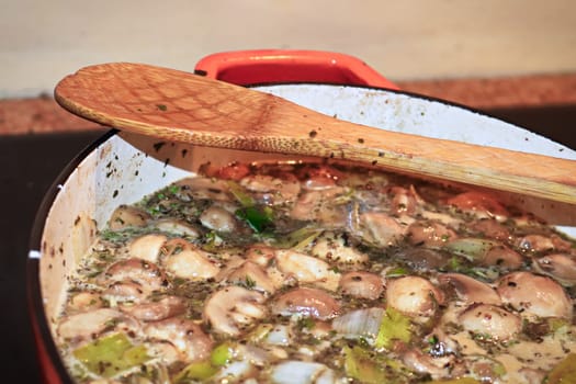 A pot of vegetables cooking with a wooden spoon on the edge.
