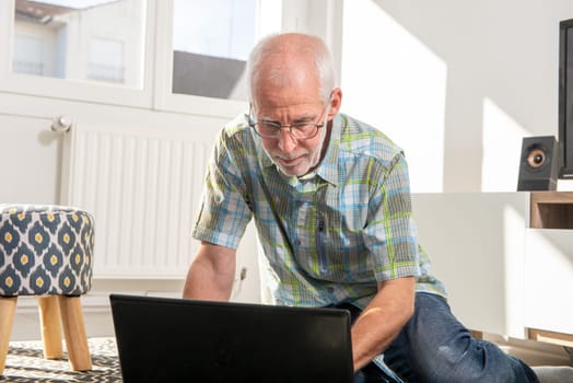Mature man lying on floor and using a laptop