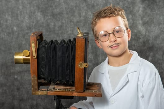 cheerful boy retro photographer with a vintage wooden camera