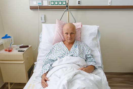Middle age woman without hair after chemotherapy patient lying at hospital bed feeling sad and depressed worried. Disease feeling sick in health care and clinical attention concept.