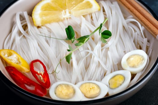 Rice noodles, Asian cuisine, with quail eggs, chili pepper and pea sprout, close-up
