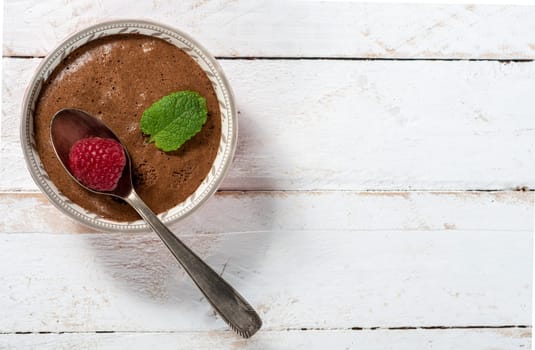 Homemade chocolate mousse with  raspberry on the white wooden background