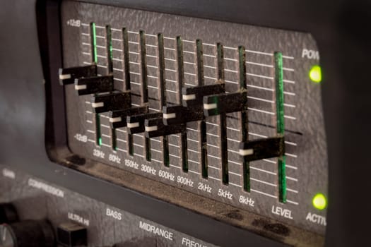Old black dusty controls of an audio equalizer from a guitar amplifier