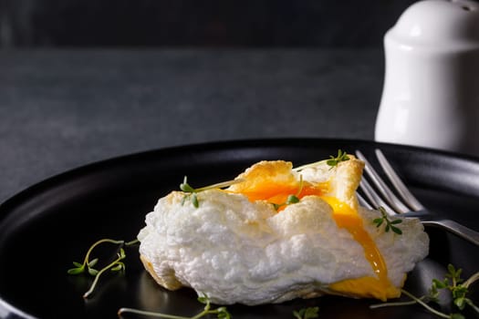 Orsini egg on a black dish with cress salad on a dark background