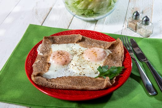 homemade Breton crepe with egg in a red plate