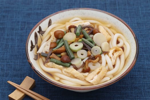 Japanese udon noodles in a ceramic bowl with chopsticks on table