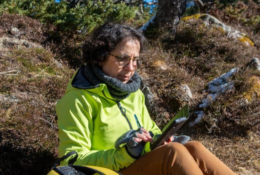 a cheerful brunette senior woman using smartphone outdoors