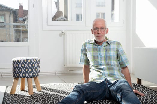 a senior man sitting on the floor in the living room