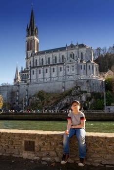 a young boy with the cathedral-sanctuary of Lourdes (France)