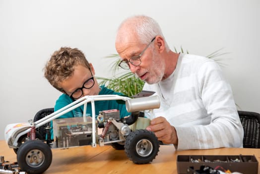 grandpa and son little boy repairing a model radio-controlled car at home
