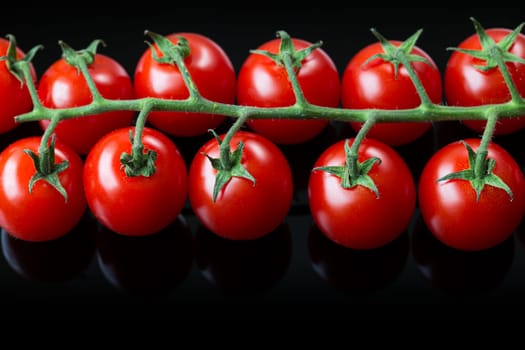 Fresh cherry tomatoes on a black background. Bunch of fresh cherry tomato on a black background