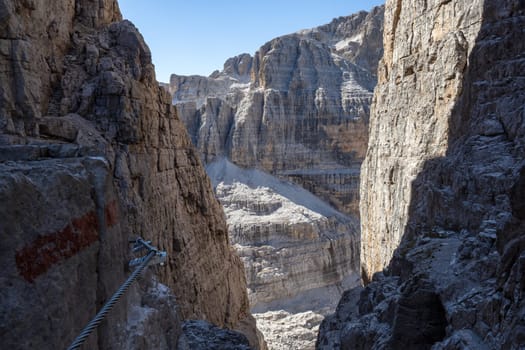 Fixed-rope Route, climbing a via ferrata route. Italian Alps. Mountain tourism in the Dolomites. Region Brenta, Italy.