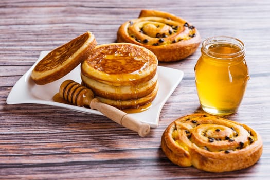 Pancakes with liquid honey on wooden background.