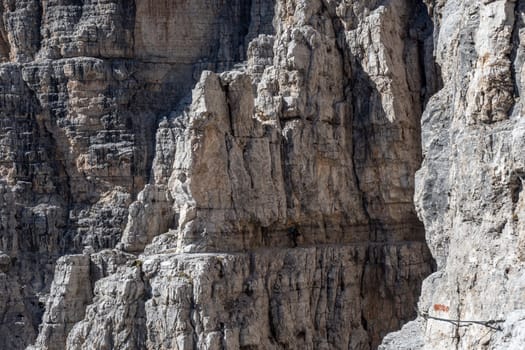 Male mountain climber on a Via Ferrata in breathtaking landscape of Dolomites Mountains in Italy. Travel adventure concept.