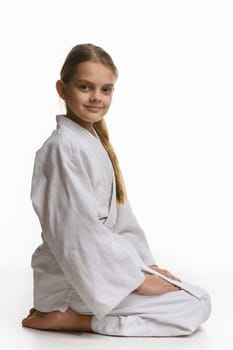 Girl in judo class, sitting on the floor, the view from the side