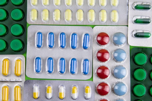 Pills of different colours lay on blue background. Colorful antibacterials pills, capsules of medicine.