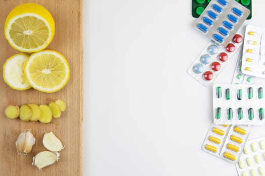 Lemon, ginger, and chapel against multi-colored tablets. The concept of choosing a healthy diet versus taking medication. Top views with clear space