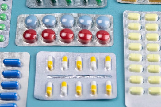 Pills of different colours lay on blue background. Colorful antibacterials pills, capsules of medicine.