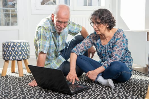 Couple senior using a computer laptop at home for online shopping