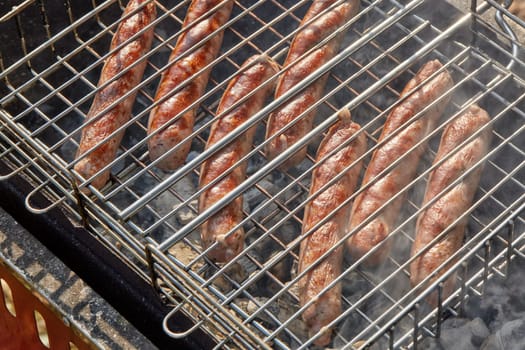 Pork sausages.  Cooking on barbecue grill ( chargrill, brazier). Top view, closeup. Outdoors. Fast food
