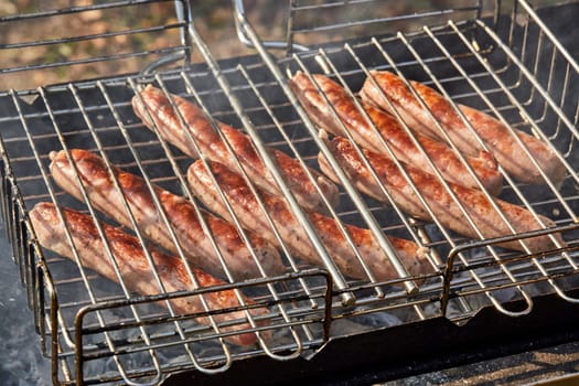 Pork sausages.  Cooking on barbecue grill ( chargrill, brazier). Top view, closeup. Outdoors. Fast food