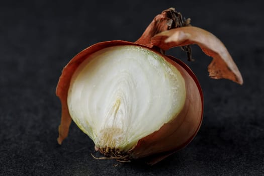 Onion half with husk on a dark background