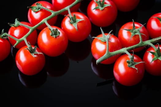 Fresh cherry tomatoes on a black background. Bunch of fresh cherry tomato on a black background