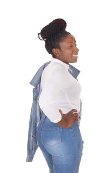 A young African American woman standing in ripped jeans with her.jacket over her shoulder and white top, isolated for white background.