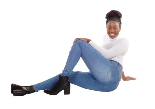 A beautiful tall African American woman sitting in jeans and white top.on the floor in the studio, isolated for white background.